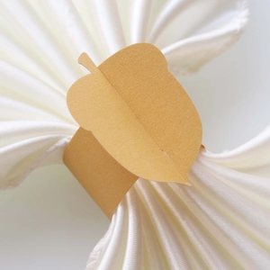 Macro detail of leaf-shaped kraft paper napkin ring on elegant white silk cloth