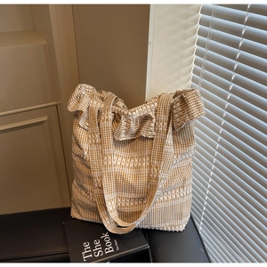Gros plan sur le sac fourre-tout en toile à carreaux beige avec bords volantés et texture