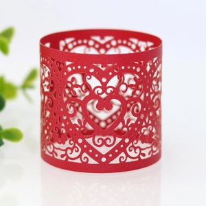 Macro detail of red laser-cut napkin ring featuring intricate hollow heart patterns