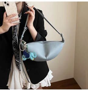 Detail of light blue crescent bag featuring pebble leather texture and elephant charm
