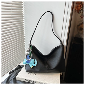 Detail of black pebble leather hobo bag with unique blue elephant charm and heart chain