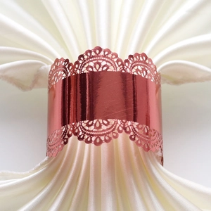 Macro view of rose gold hollow-out lace napkin ring with laser-cut floral patterns
