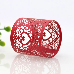Macro detail of red laser-cut heart napkin rings with floral vine patterns for weddings