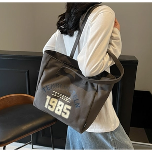 Détail du sac cabas en toile taupe avec lettrage vintage 1985 et étiquette tissée
