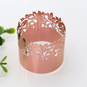 Macro detail of laser-cut rose gold napkin ring with hollow floral patterns for wedding decor
