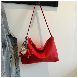 Detailed texture of red lychee pattern tote bag with a cute elephant pendant on a wall
