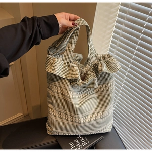 Détail du sac cabas en toile à carreaux verts avec bords volantés et broderies blanches
