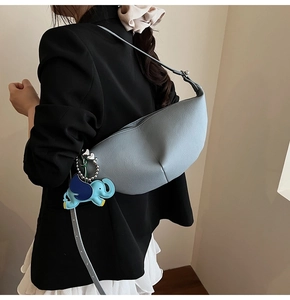 Detail view of light blue leather dumpling bag with adorable elephant charm on shoulder