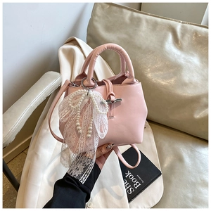 Detail of pink PU leather handbag featuring elegant pearl lace bow and silver hardware