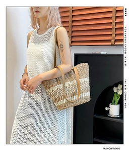 Detail of woven straw tote bag with dual-tone texture and premium brown leather handles