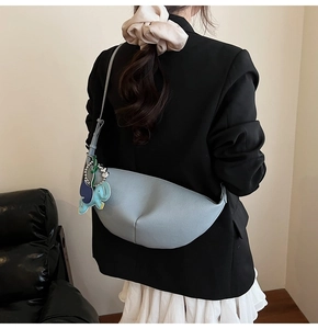 Sky blue crescent dumpling bag with elephant charm worn with casual attire