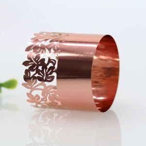Close-up of rose gold napkin ring with hollow floral pattern and polished mirror finish