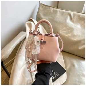 Detail of pink PU leather handbag featuring a white lace bow and pearl tassel charm