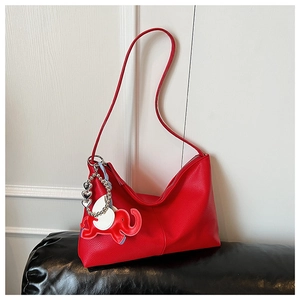 Detail of red pebbled leather tote bag with elephant charm and silver heart chain
