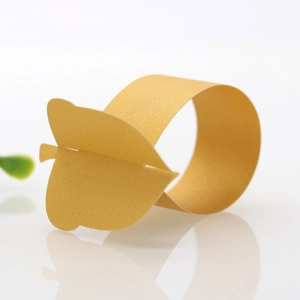 Macro shot of gold leaf-shaped napkin ring with metallic luster on white background