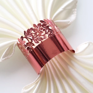 Close-up of rose gold hollow leaf napkin ring on elegant white satin fabric