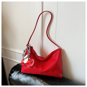 Close-up of a red textured leather tote bag featuring a cute elephant charm accessory
