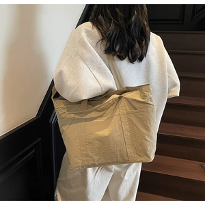 Detail of khaki pleated nylon tote bag featuring durable straps for daily commute