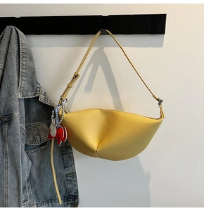 Detail of yellow lychee leather dumpling bag with elephant charm and pleated structure
