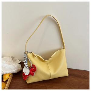 Detail of yellow lychee texture leather shoulder bag with elephant charm and heart chain