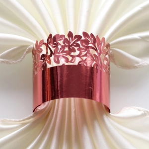 Close-up of rose gold laser-cut floral napkin ring on white satin fabric for dining decor