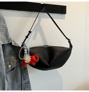 Detail view of black lychee-grain crescent bag with a cute red elephant charm accessory