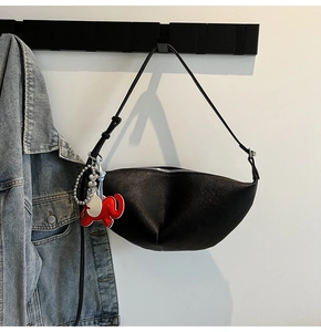 Detail of black pebbled leather dumpling bag featuring a red elephant charm and white beads