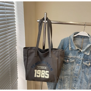 Vue détaillée du sac cabas en toile gris foncé avec lettres bleues et imprimés chiffres