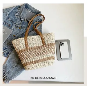 Detail of woven straw tote bag with brown leather handles and striped texture