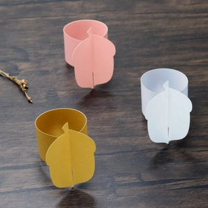 Close-up of paper napkin rings with 3D leaf designs in pink, white, and frosted gold