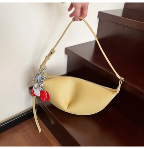 Detail of yellow hobo dumpling bag with lychee texture and red elephant charm