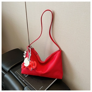 Detail of red pebbled leather hobo bag with elephant charm on black sofa setting