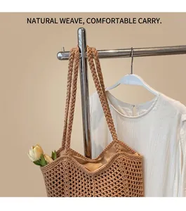 Detail of woven straw tote bag featuring thick braided shoulder straps and hollow-out design