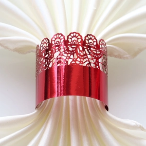 Close-up of red metal napkin ring with hollow crown lace design for wedding decor