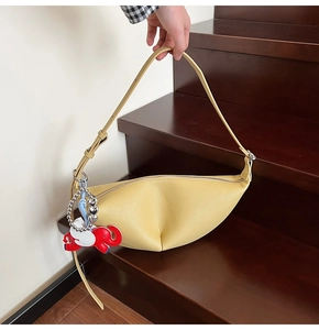 Detail of light yellow crescent shoulder bag with litchi grain leather and elephant charm