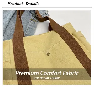 Detail of yellow canvas tote bag with thick brown strap and vintage metal rivet