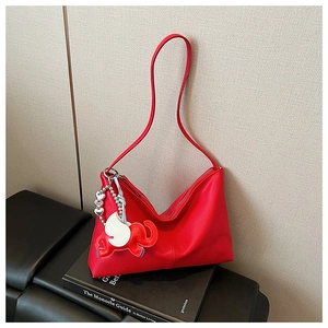 Detail of red pebbled leather shoulder bag with cute elephant charm and silver hardware