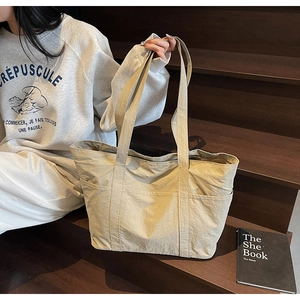 Detail of light khaki tote bag with pleated texture and functional side pockets