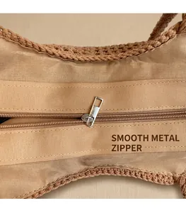 Detail of smooth silver zipper and woven texture on a tan summer beach tote bag