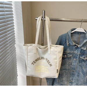Gros plan d'un sac cabas en toile crème avec typographie vintage sur un support