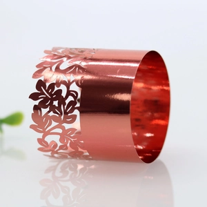 Detail of rose gold napkin ring featuring intricate laser-cut floral patterns and metal finish