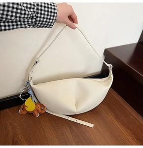 Detail of cream-white crescent shoulder bag with litchi texture and elephant charm