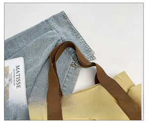 Close-up of yellow canvas tote bag showing reinforced brown cotton shoulder strap detail