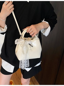 Elegant cream leather handbag with lace pearl bow and tassel chain shown on model