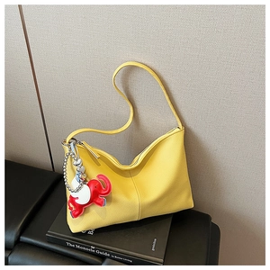 Detail of yellow pebbled leather tote with red elephant charm and silver heart chain