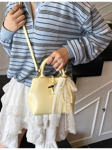 Mini yellow crossbody bag with pearl lace pendant shown in a stylish casual lifestyle setting