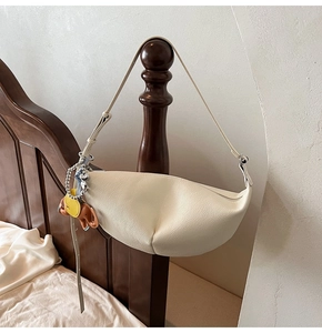 Detail of white lychee leather dumpling bag with cute animal charms hanging on wood