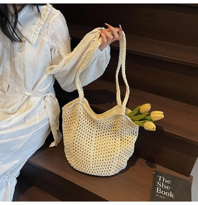 Detailed close-up of a beige woven crochet tote bag with round handles on wooden stairs