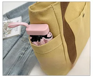 Detail of canvas tote bag side pocket holding a small folding umbrella for daily use
