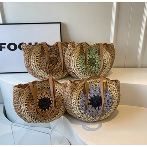 Detail of straw woven tote bags with large sunflower patterns and brown leather handles